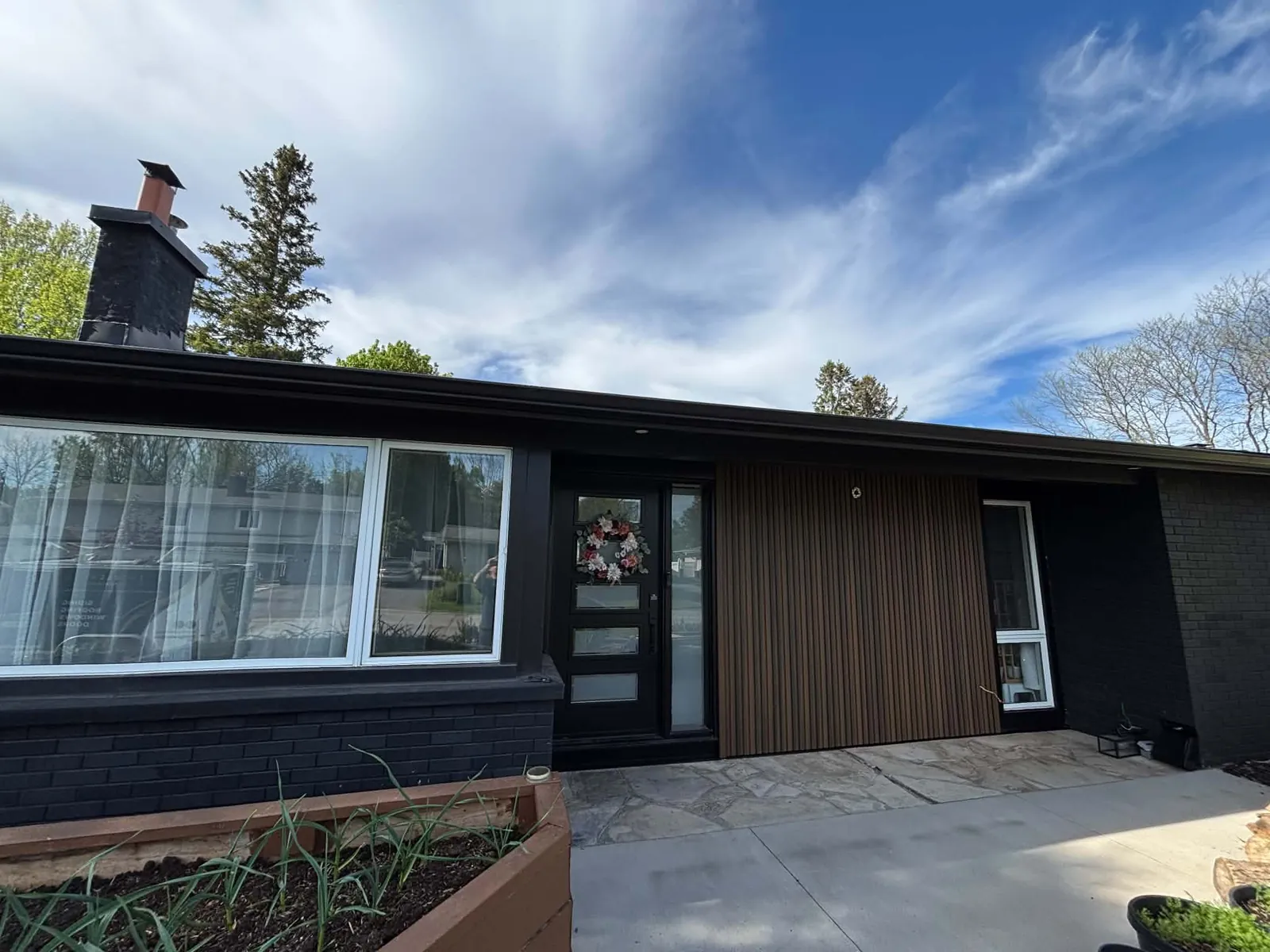 Nepean, Ottawa bungalow with black brick and a warm Fiberwood fluted wood siding feature wall beside the front door