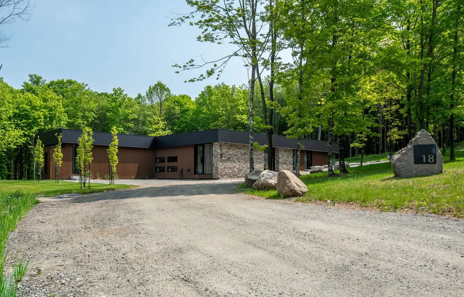 Modern single-storey Navan, Ottawa home on a wooded lot with new wood-look siding and charcoal metal fascia