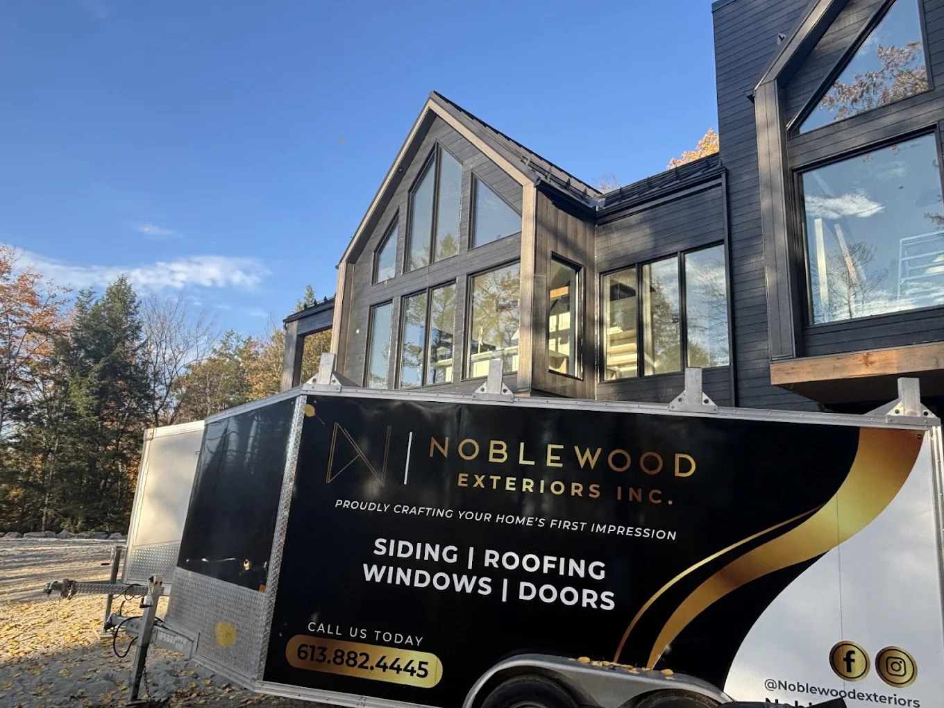 Noblewood Exteriors branded trailer in front of a home under construction