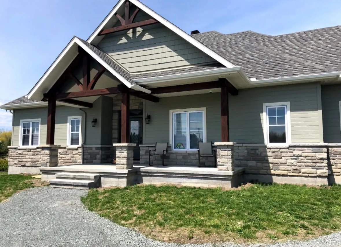 Front porch of a Stittsville home with sage-green wood composite lap siding, white trim and timber posts